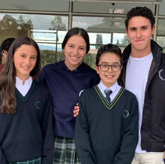 Cuatro estudiantes del colegio, sonrientes, con el uniforme de Cumbres